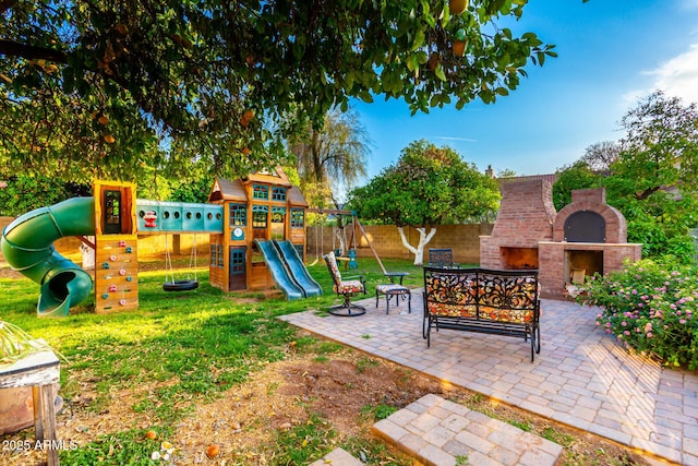 view of playground featuring an outdoor brick fireplace and a patio