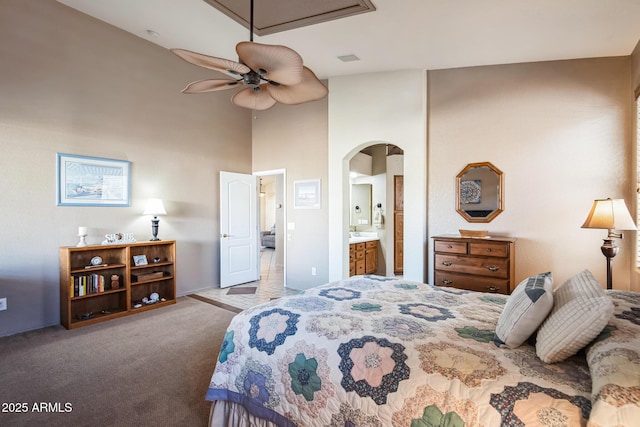 carpeted bedroom featuring connected bathroom, ceiling fan, and a high ceiling