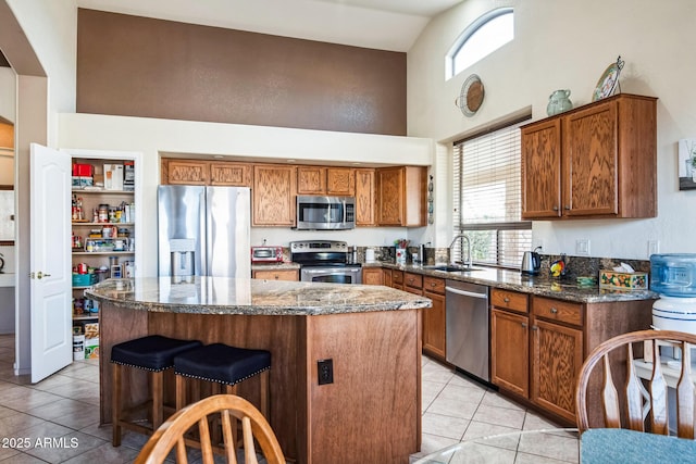 kitchen featuring dark stone counters, a breakfast bar, stainless steel appliances, sink, and a kitchen island