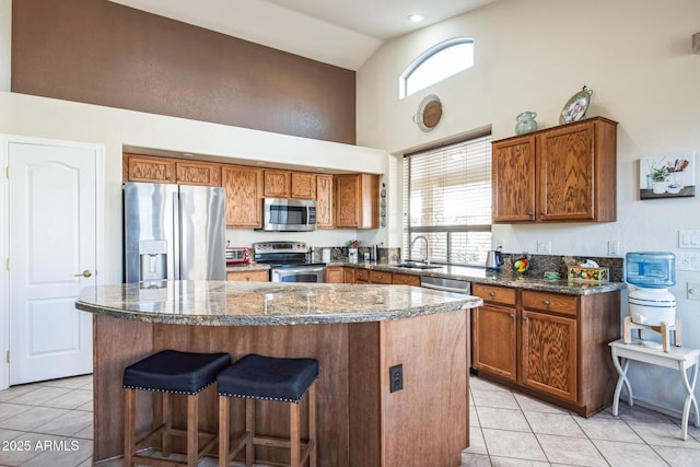 kitchen featuring a kitchen island, sink, light tile patterned floors, and stainless steel appliances