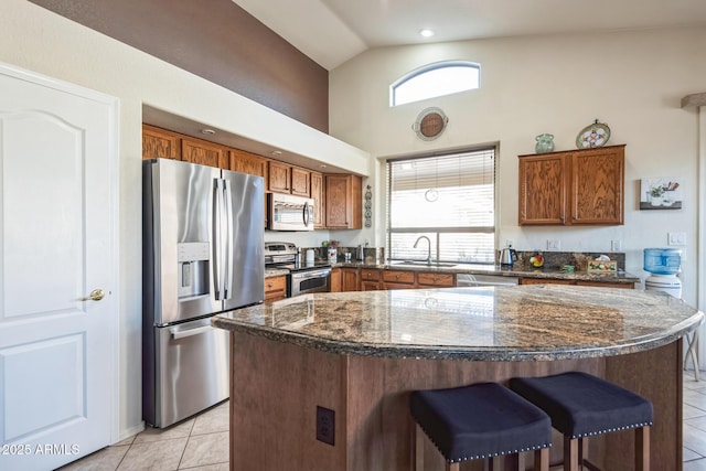 kitchen featuring lofted ceiling, sink, light tile patterned floors, a kitchen island, and stainless steel appliances