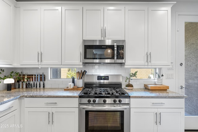 6338 W Raymond St, Phoenix, AZ 85043 - kitchen featuring appliances with stainless steel finishes, white cabinets, backsplash, and light stone counters