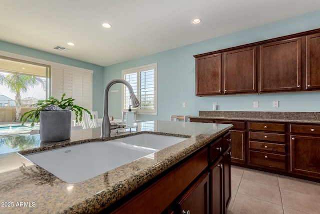 kitchen featuring light tile patterned flooring, light stone counters, and sink