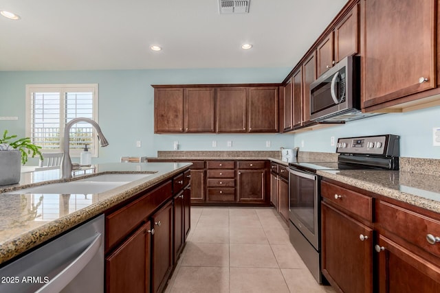 kitchen featuring light stone countertops, sink, appliances with stainless steel finishes, and light tile patterned floors