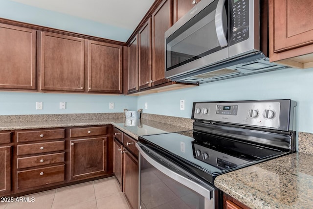 kitchen with appliances with stainless steel finishes, light tile patterned flooring, and light stone counters