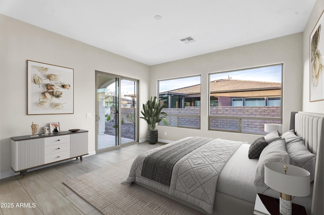 bedroom featuring access to exterior, visible vents, baseboards, and wood finish floors