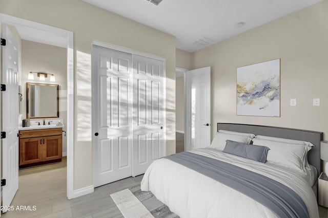 bedroom with a closet, visible vents, a sink, and ensuite bathroom