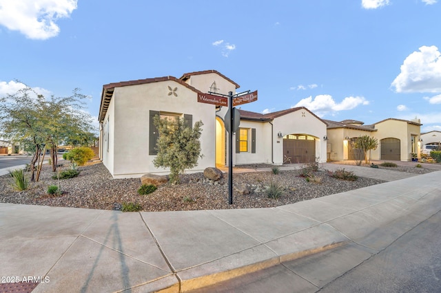 mediterranean / spanish-style home featuring an attached garage, driveway, and stucco siding