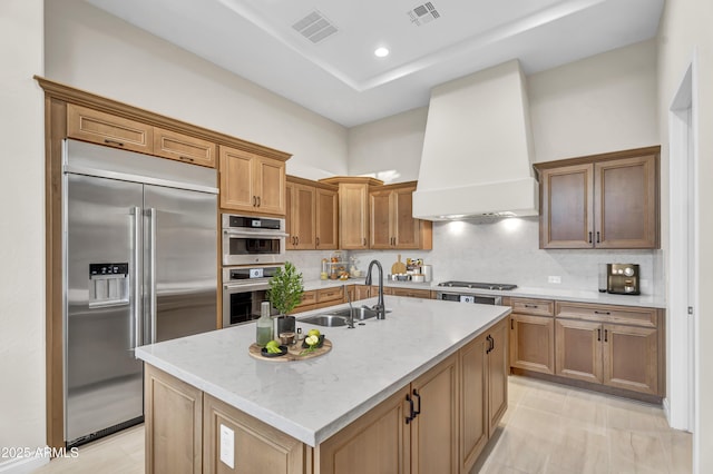 kitchen featuring stainless steel appliances, a sink, visible vents, a center island with sink, and custom range hood