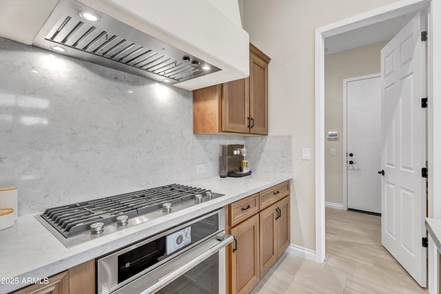 kitchen with appliances with stainless steel finishes, light countertops, brown cabinets, and custom range hood