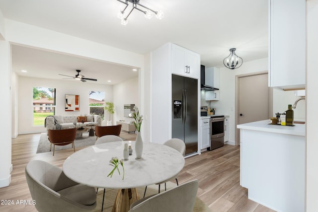 dining area featuring ceiling fan with notable chandelier, light hardwood / wood-style flooring, and sink