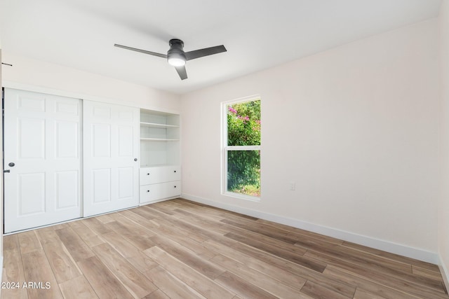 unfurnished bedroom with ceiling fan, light wood-type flooring, and a closet