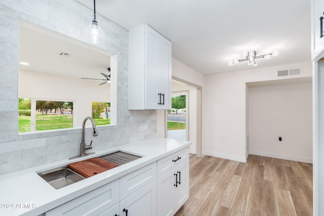 kitchen featuring white cabinets, pendant lighting, a healthy amount of sunlight, and sink