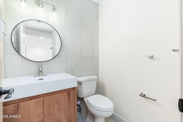 bathroom featuring vanity, toilet, and tile walls