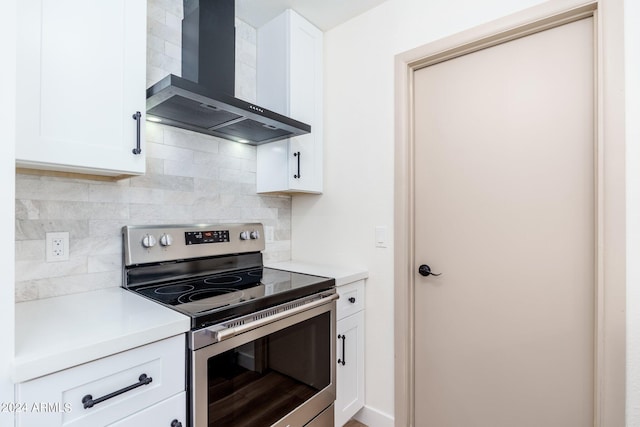 kitchen with stainless steel electric stove, white cabinetry, tasteful backsplash, and wall chimney range hood