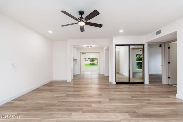 empty room featuring light hardwood / wood-style flooring and ceiling fan with notable chandelier