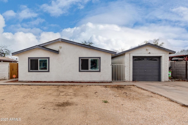 ranch-style house featuring a garage, stucco siding, driveway, and fence