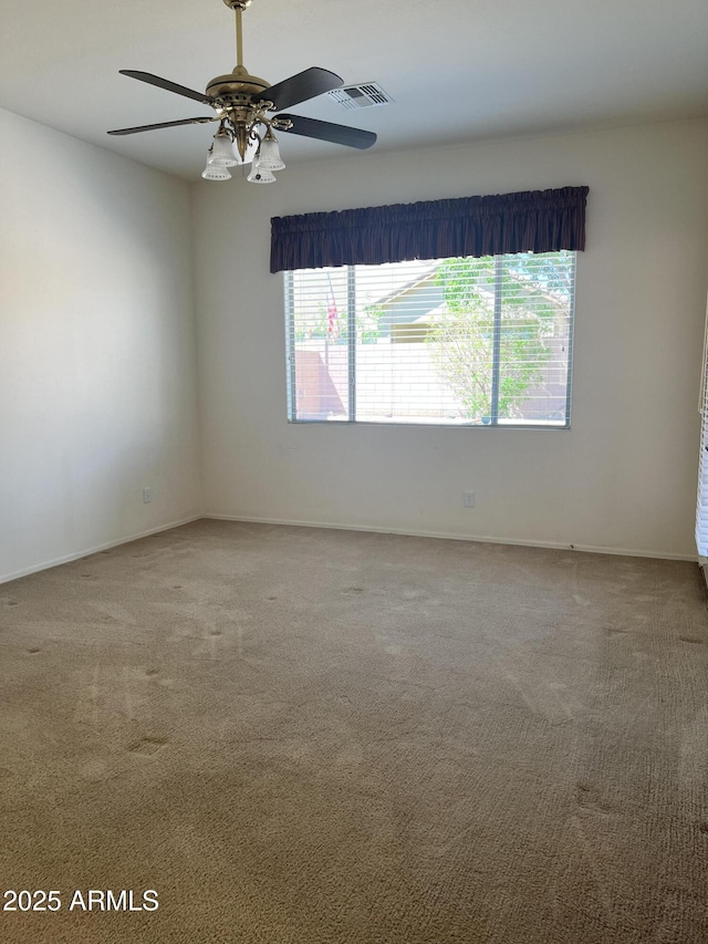 spare room with carpet floors, a healthy amount of sunlight, a ceiling fan, and visible vents
