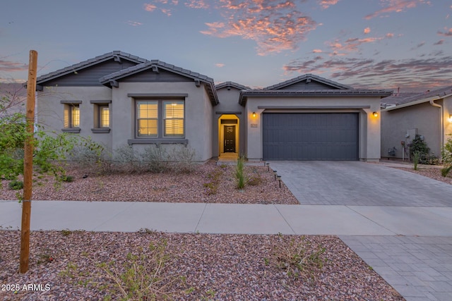 view of front of home featuring a garage, decorative driveway, a tile roof, and stucco siding