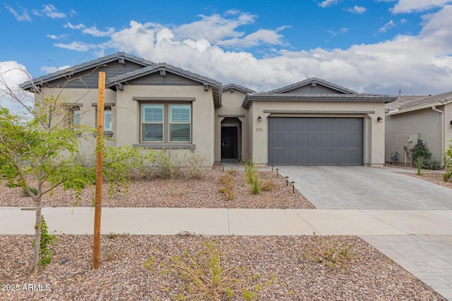 view of front of property featuring a garage, a tiled roof, decorative driveway, and stucco siding