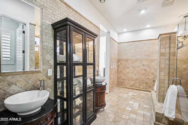 bathroom with tile walls, tiled shower, an inviting chandelier, and vanity