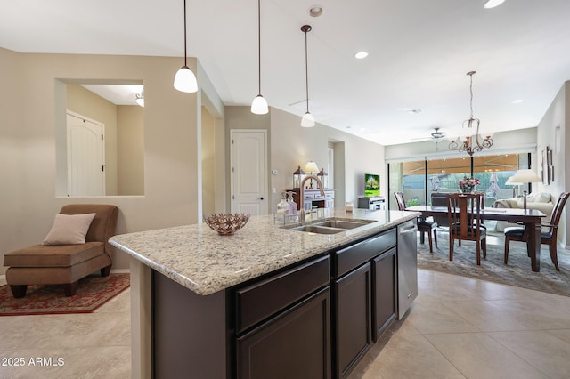 kitchen with light stone counters, dark brown cabinetry, sink, pendant lighting, and an island with sink