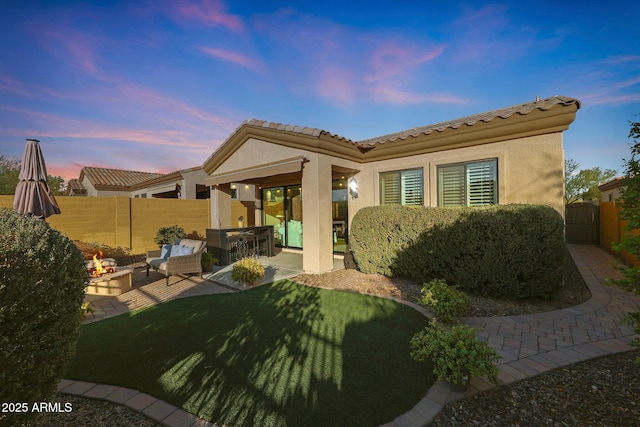 back house at dusk with a lawn, an outdoor hangout area, and a patio