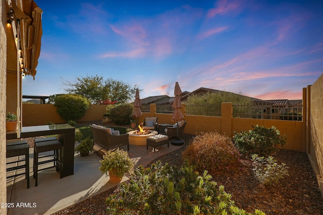 patio terrace at dusk with an outdoor living space with a fire pit