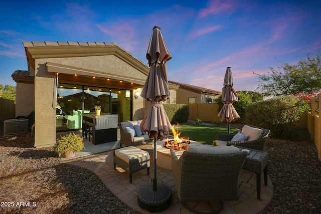 patio terrace at dusk with central AC and an outdoor living space