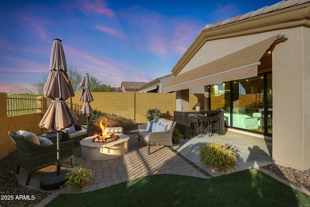 patio terrace at dusk featuring a fire pit and exterior bar