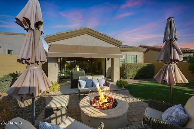 patio terrace at dusk featuring a yard and an outdoor fire pit