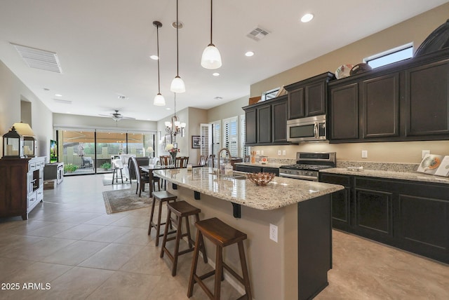 kitchen featuring sink, hanging light fixtures, ceiling fan, an island with sink, and stainless steel appliances