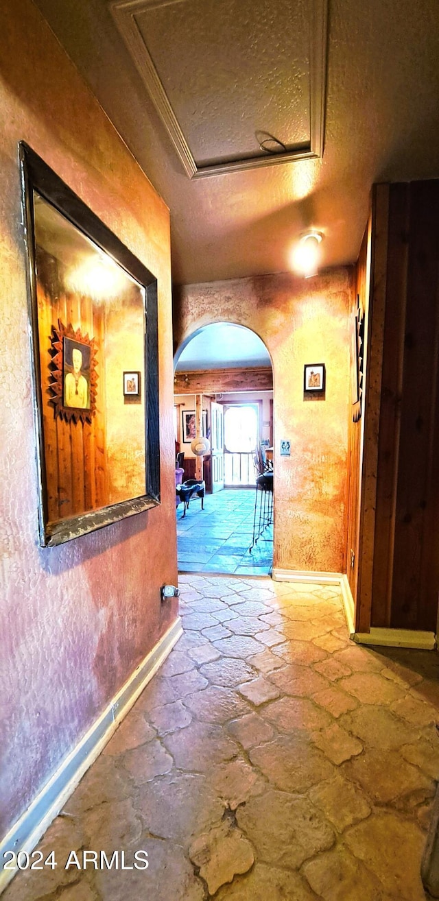 corridor with a textured ceiling and ornamental molding