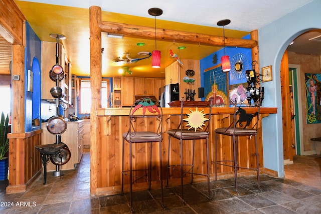 bar featuring wood walls, stainless steel fridge, and hanging light fixtures