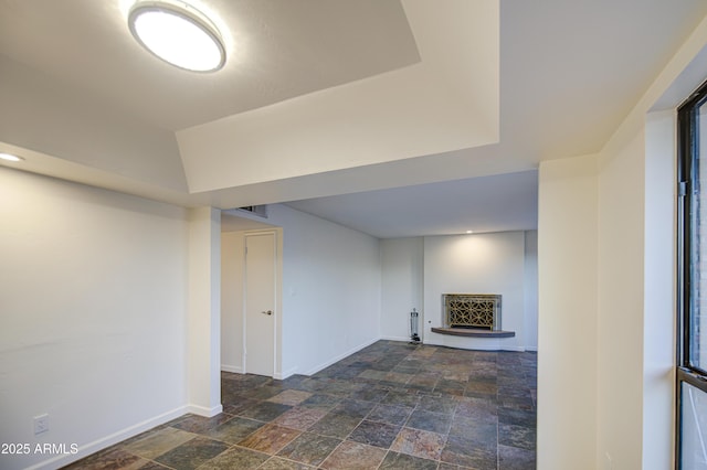 finished below grade area featuring stone finish flooring, a fireplace with raised hearth, and baseboards