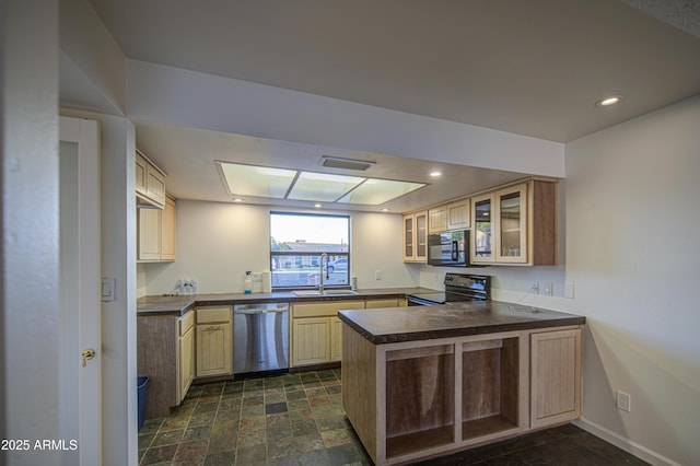 kitchen featuring glass insert cabinets, a sink, appliances with stainless steel finishes, dark countertops, and a peninsula