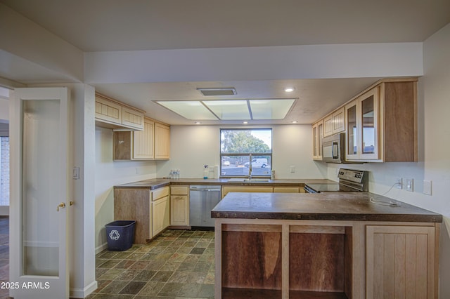 kitchen with appliances with stainless steel finishes, stone finish flooring, visible vents, dark countertops, and a peninsula