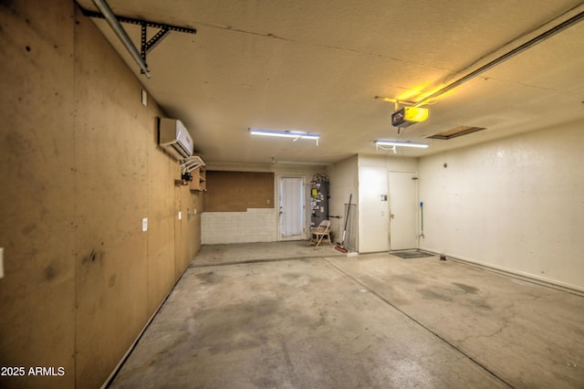 garage featuring a garage door opener, secured water heater, and an AC wall unit