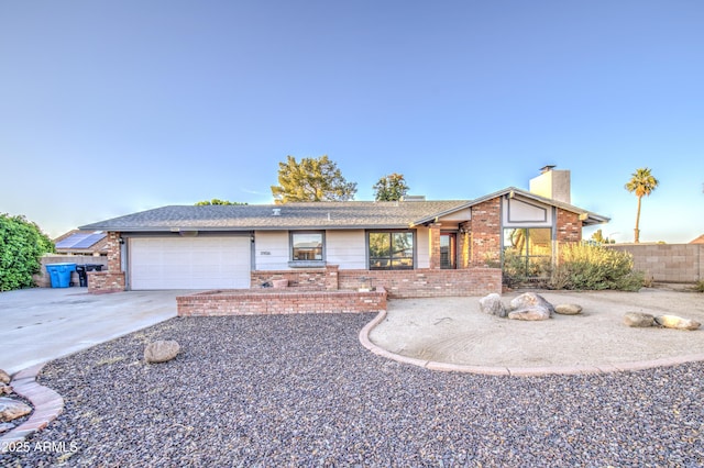 ranch-style house featuring a chimney, brick siding, fence, a garage, and driveway