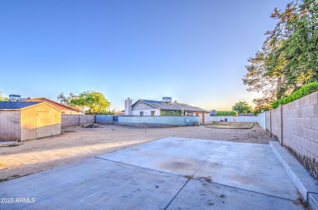 view of patio featuring a fenced backyard, an outbuilding, and a storage shed