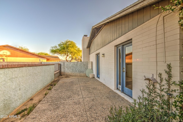 view of side of home featuring a chimney, a patio, and a fenced backyard