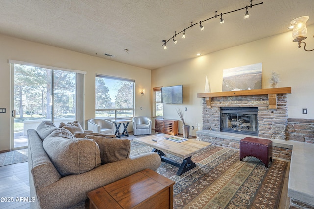 living room featuring a textured ceiling, track lighting, a fireplace, and hardwood / wood-style flooring