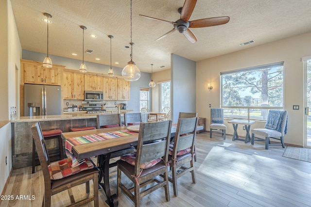 dining space featuring a textured ceiling, ceiling fan, and light wood-type flooring