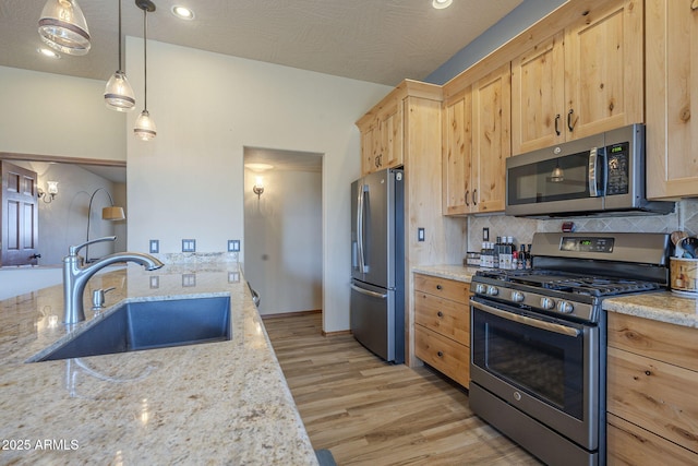 kitchen with appliances with stainless steel finishes, pendant lighting, light brown cabinetry, sink, and tasteful backsplash