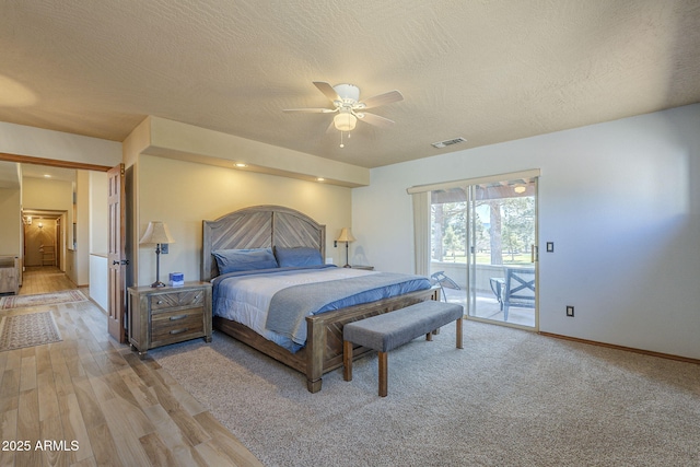 bedroom with light hardwood / wood-style floors, a textured ceiling, ceiling fan, and access to outside