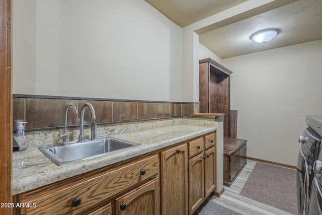 kitchen with light stone countertops, light hardwood / wood-style flooring, and sink