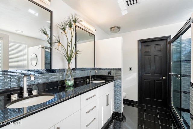 bathroom with toilet, double vanity, visible vents, and a sink