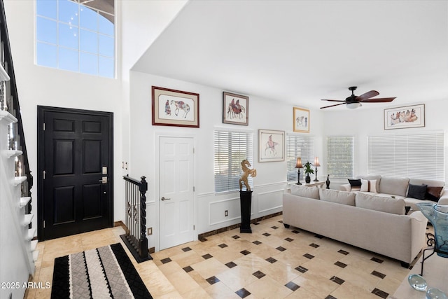 foyer entrance featuring light tile patterned flooring, a wainscoted wall, a decorative wall, and ceiling fan