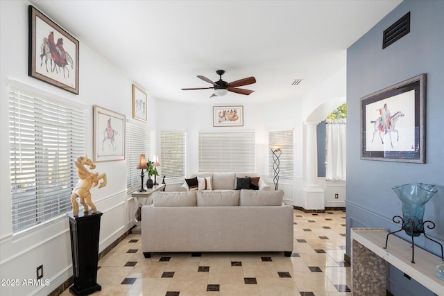 living area featuring a ceiling fan, plenty of natural light, visible vents, and ornate columns