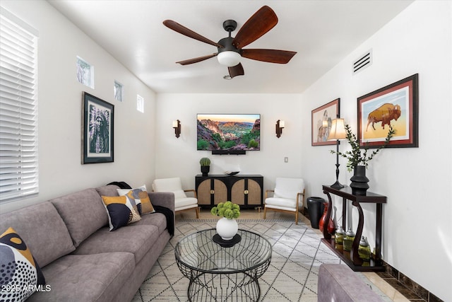 living room featuring baseboards, visible vents, and a ceiling fan